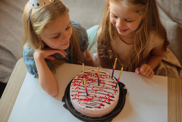 A little girl on her birthday sits on the floor next to
scattered confetti from a festive hatxachild celebrates his
birthday at home during illness quarantine isolation holiday
without guests