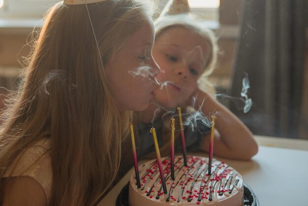 A little girl on her birthday sits on the floor next to
scattered confetti from a festive hatxachild celebrates his
birthday at home during illness quarantine isolation holiday
without guests