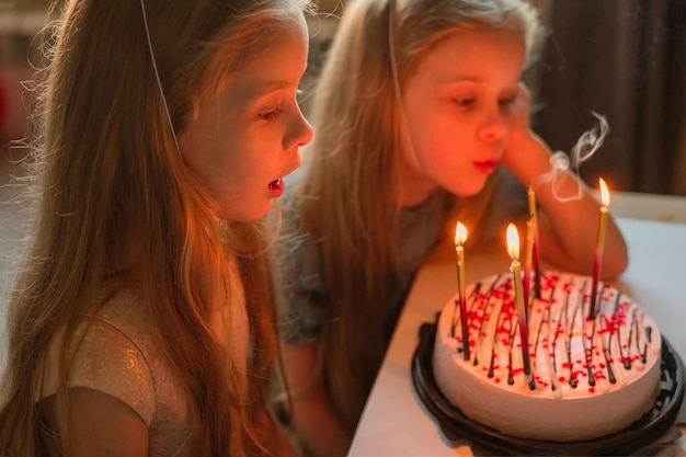 생일을 맞은 어린 소녀는 축제 모자에서 흩어진 색종이 조각 옆 바닥에 앉아 있습니다.xAchild는 손님이 없는 질병 격리 휴가 기간 동안 집에서 생일을 축하합니다