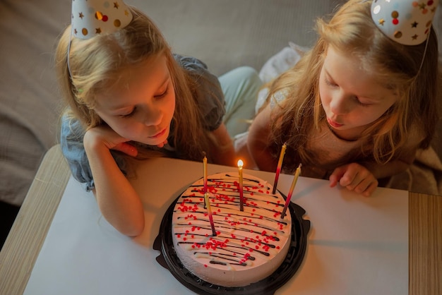 생일을 맞은 어린 소녀는 축제 모자에서 흩어진 색종이 조각 옆 바닥에 앉아 있습니다.xAchild는 손님이 없는 질병 격리 휴가 기간 동안 집에서 생일을 축하합니다