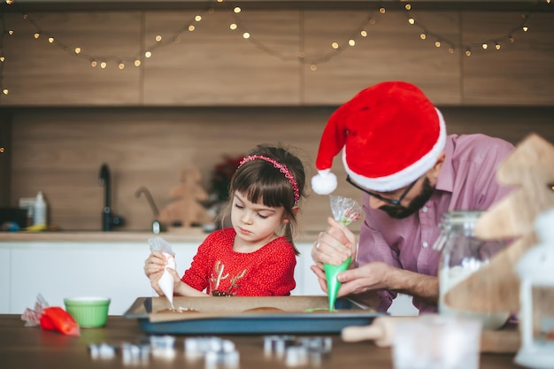 Little girl and her father decorating cookies