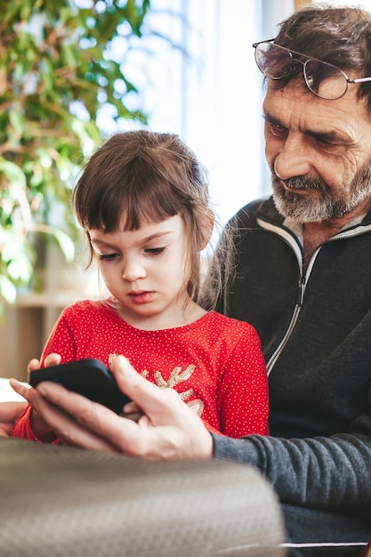 Little girl and her grandfather using mobile