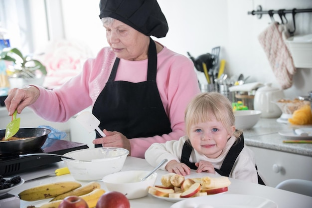 A little girl and her grandmother cooking in the kitchen