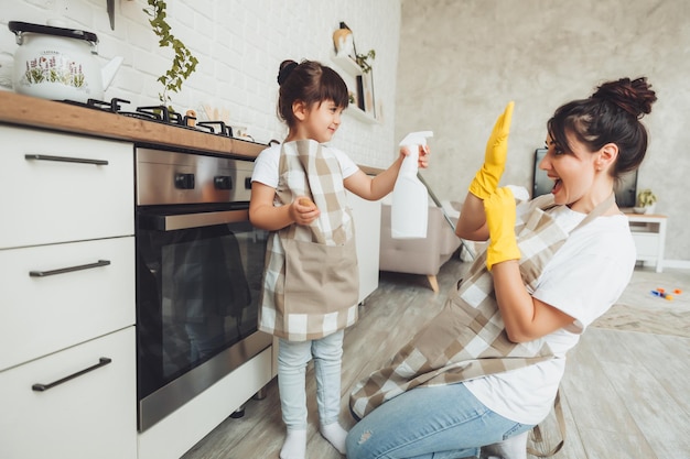 A little girl and her mother are cleaning the kitchen a woman and a child wipe the oven in the kitchen house cleaning helping mom