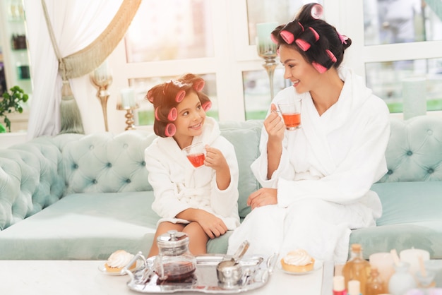 A little girl and her mother are sitting on couch 