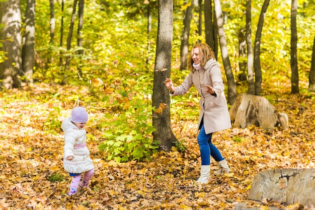 秋の公園で遊んでいる少女と彼女の母親。