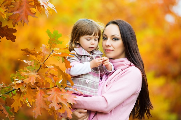 Little girl and her mother playing in the autumn park.