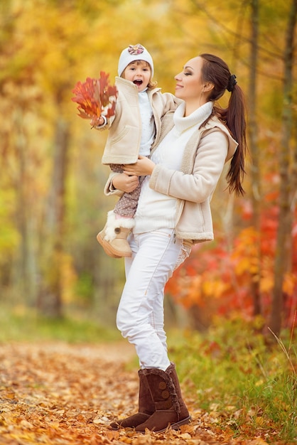 秋の公園で遊んでいる少女と彼女の母親。