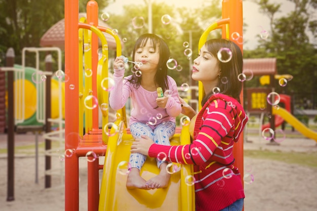 Little girl and her mother plays with soap bubbles