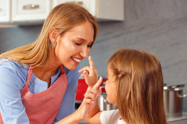 Little girl and her mother stain each other noses with flour