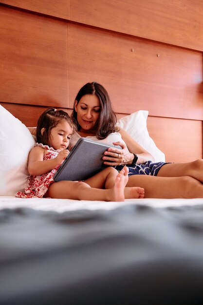 Foto bambina e sua madre usano un ipad in una stanza d'albergo