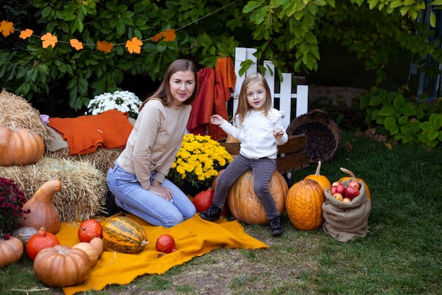 Little girl and her mother with pumpkins