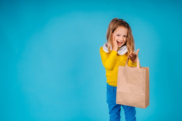 Photo a little girl hold paper bags amased looking at camera.