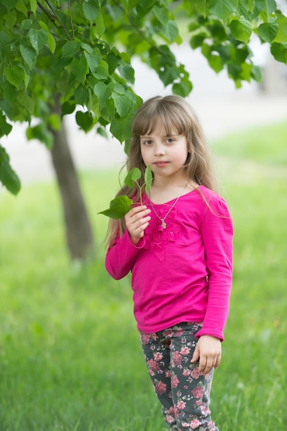 Little girl hold young green plant in sunlight. Ecology concept.