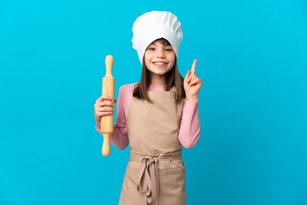 素晴らしいアイデアを指している青い壁に分離された麺棒を持っている少女