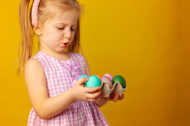 Little girl holding basket with colored eggs. easter concept