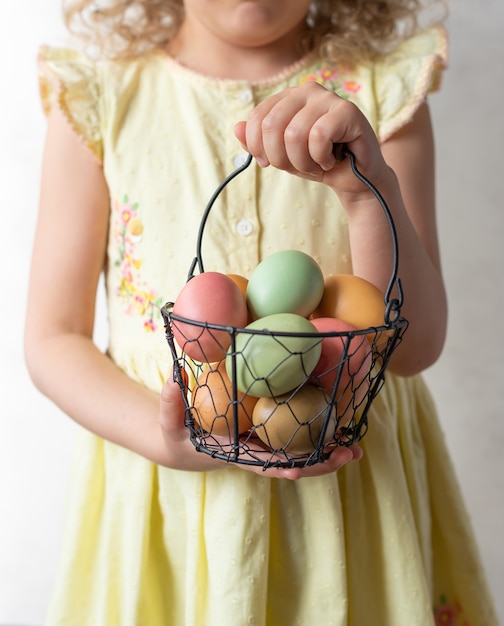 Little girl holding basket with pastel Easter eggs. Happy Easter concept