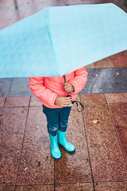 Foto piccola ragazza con un grande ombrello blu durante una passeggiata in una piovosa e buia giornata d'autunno