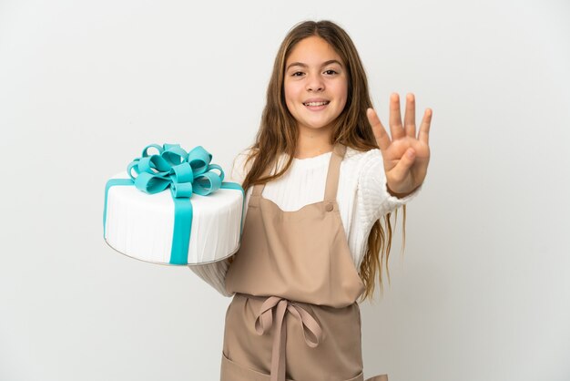 Little girl holding a big cake over isolated white background happy and counting four with fingers