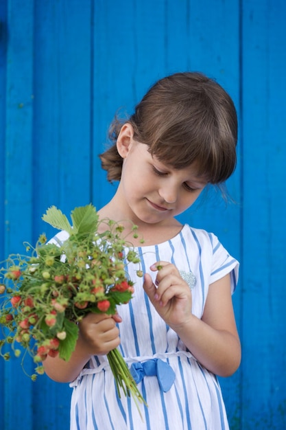 野生のイチゴの茂みを保持している少女