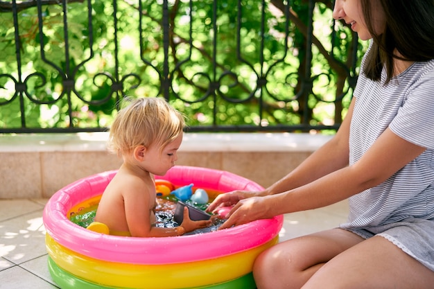 Bambina che tiene un mestolo in mano mentre è seduta in una piscina gonfiabile