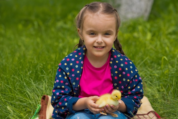 Little girl holding a duckling in her hands