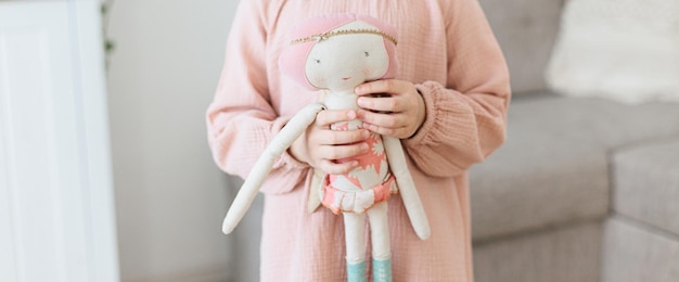 Little girl holding fabric doll at home