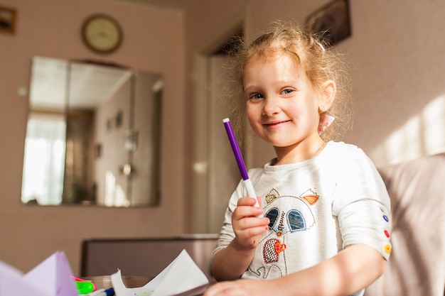 Little girl holding a felt-tip pen and laughing