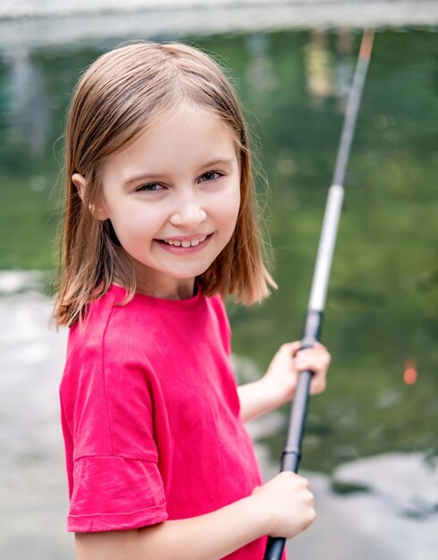 Premium Photo  Little girl holding fishing rod on pond background