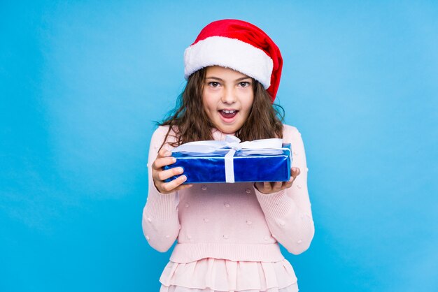 Little girl holding a gift celebrating christmas day