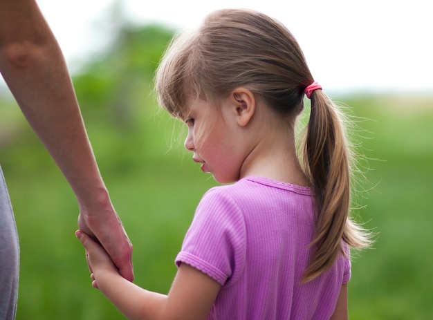 Little girl holding a hand of her mother. Family relations concept.