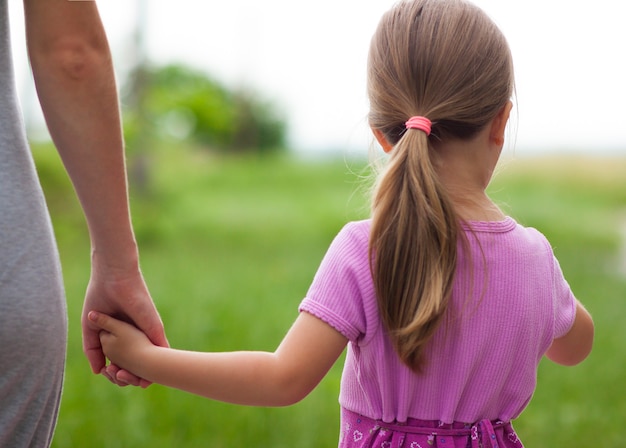 Little girl holding a hand of her mother. Family relations concept.