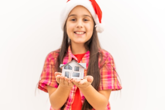Маленькая девочка держит свой глиняный дом - концепция счастливого дома, рождество, изолированная