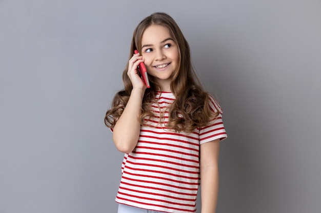 Bambina che tiene il telefono vicino al suo orecchio che parla con gli amici tariffa favorevole per le chiamate in roaming