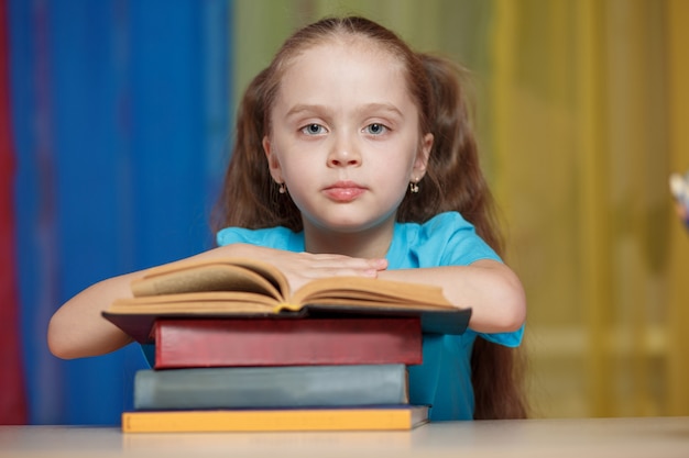 Bambina che tiene una pila di libri. di nuovo a scuola