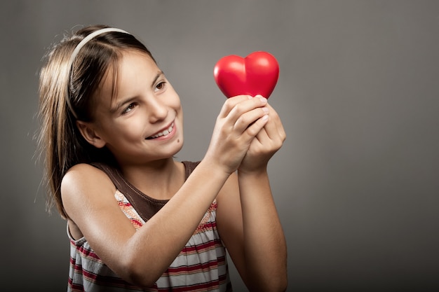 Маленькая девочка держит красное сердце