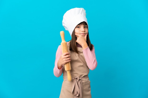 Little girl holding a rolling pin isolated