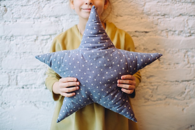 Little girl holding a star pillow