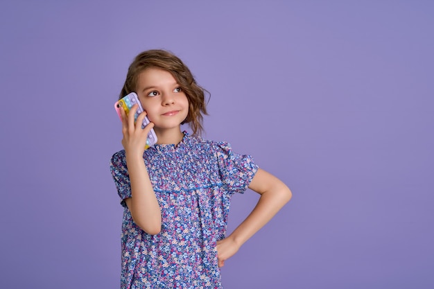 Little girl holding telephone isolated over violet color background