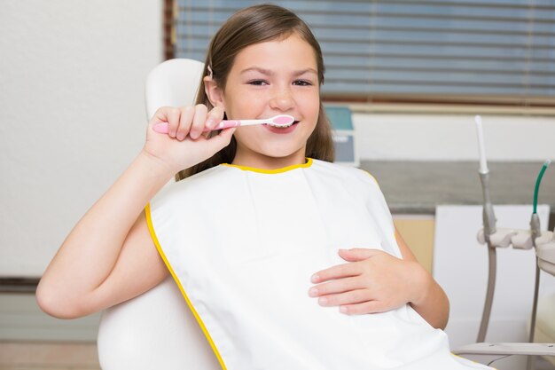 Little girl holding toothbrush in dentists chair