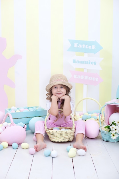 Little Girl holds a basket with Easter multicolored eggs.