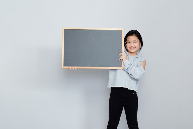 A little girl holds a blank chalkboard