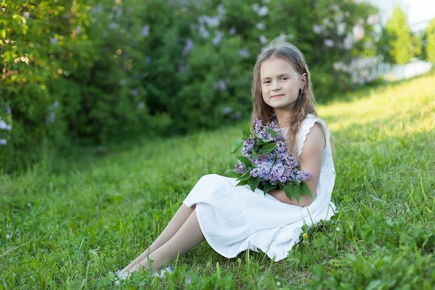 晴れた日に小さな女の子がライラックの花束を持っています。