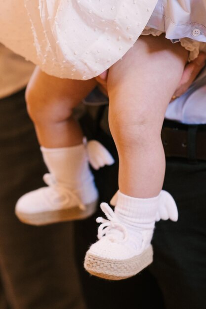 Photo little girl holds dad in her arms on the leg are white socks with angel wings