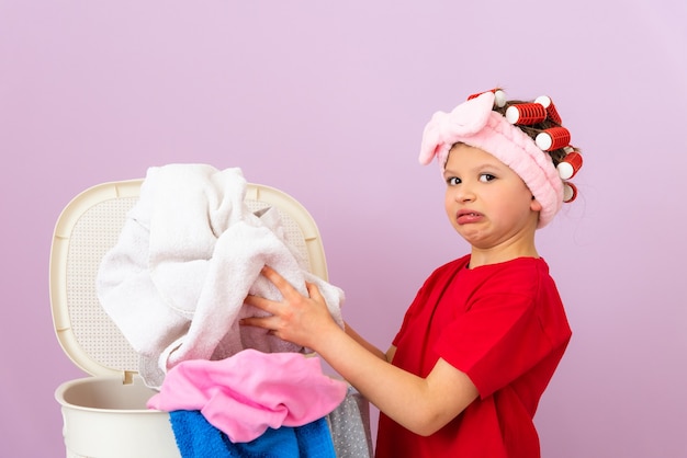 A little girl holds dirty underwear from a basket. Cleaning the house.