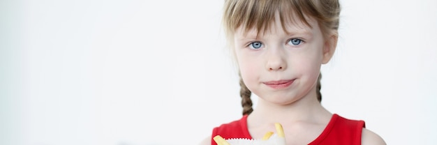 Little girl holds french fries in package in her hands. Improper and unhealthy nutrition in children concept