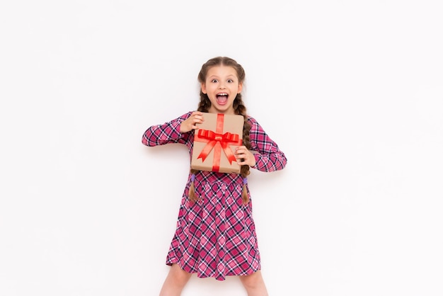 A little girl holds a gift and smiles broadly Birthday of the little princess The concept of the holiday White isolated background