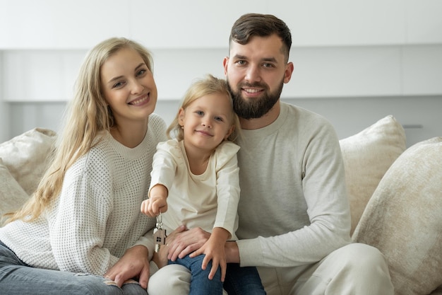 Little girl holds the keys to a new family home in her hands portrait of a smiling young married