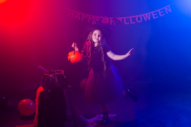 Маленькая девочка держит тыквенный разъем на празднике хэллоуина ребенок девочка носит костюм ведьмы фэнтезийная сказка
