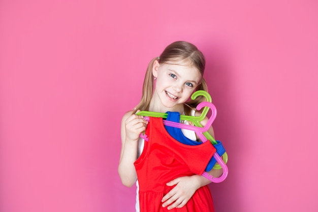 写真 小さな女の子が異なる色の2つのドレスを保持します